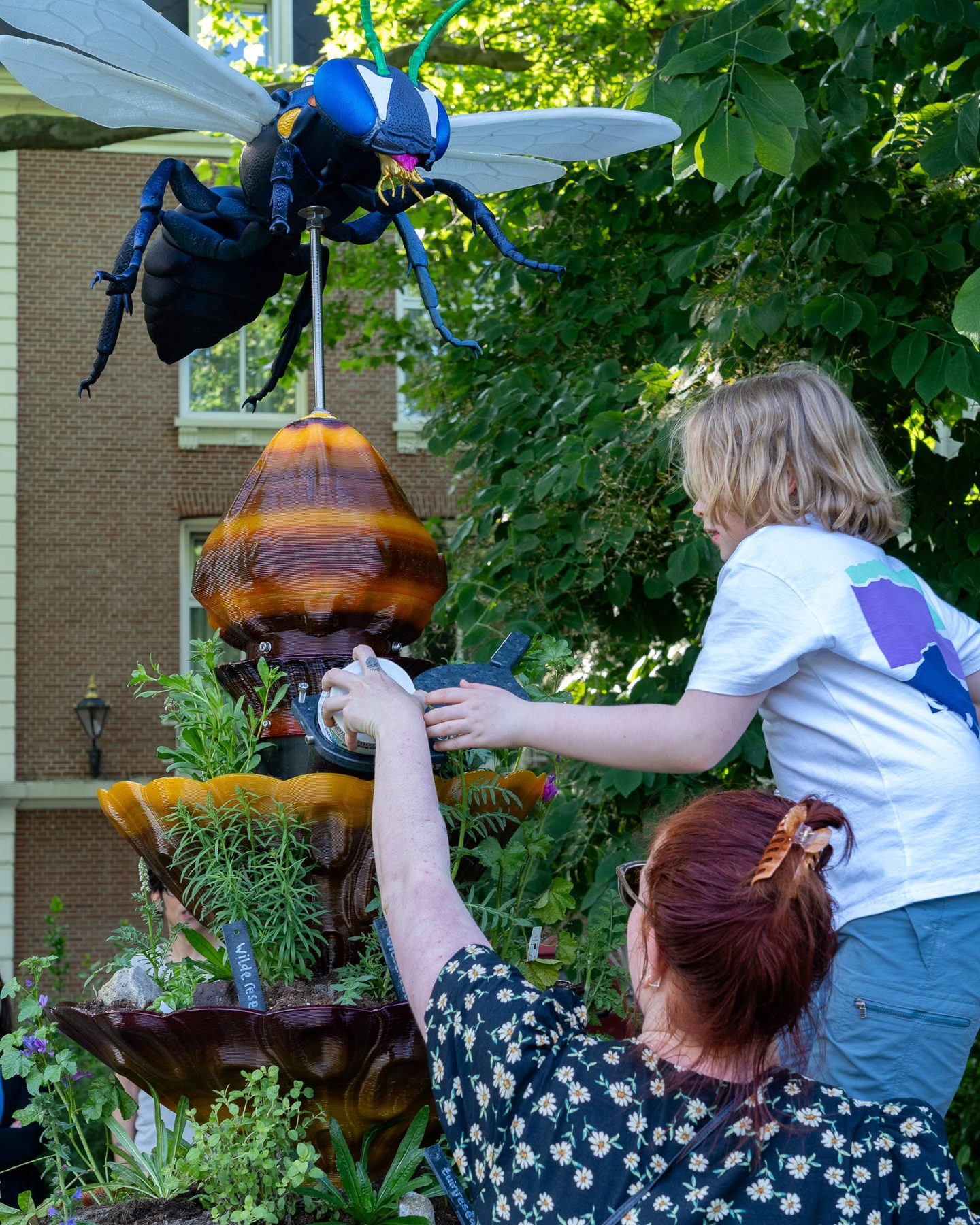 Eine Anwohnerin und ein Kind pflanzen an einem BeeTotem