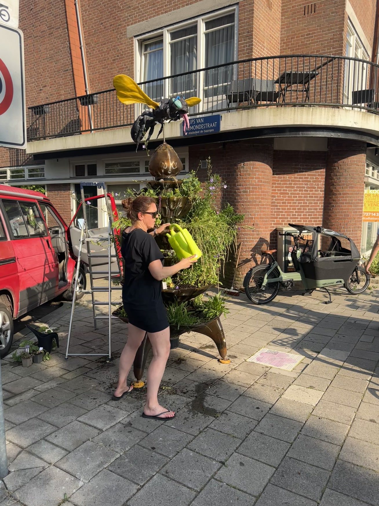 Een bewoner geeft de planten van een BeeTotem water